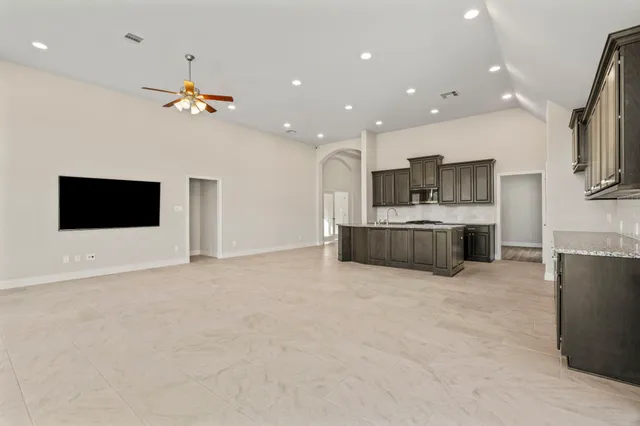 a large white kitchen with a large counter top space stainless steel appliances and a chandelier