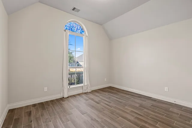 a view of an empty room with window and wooden floor