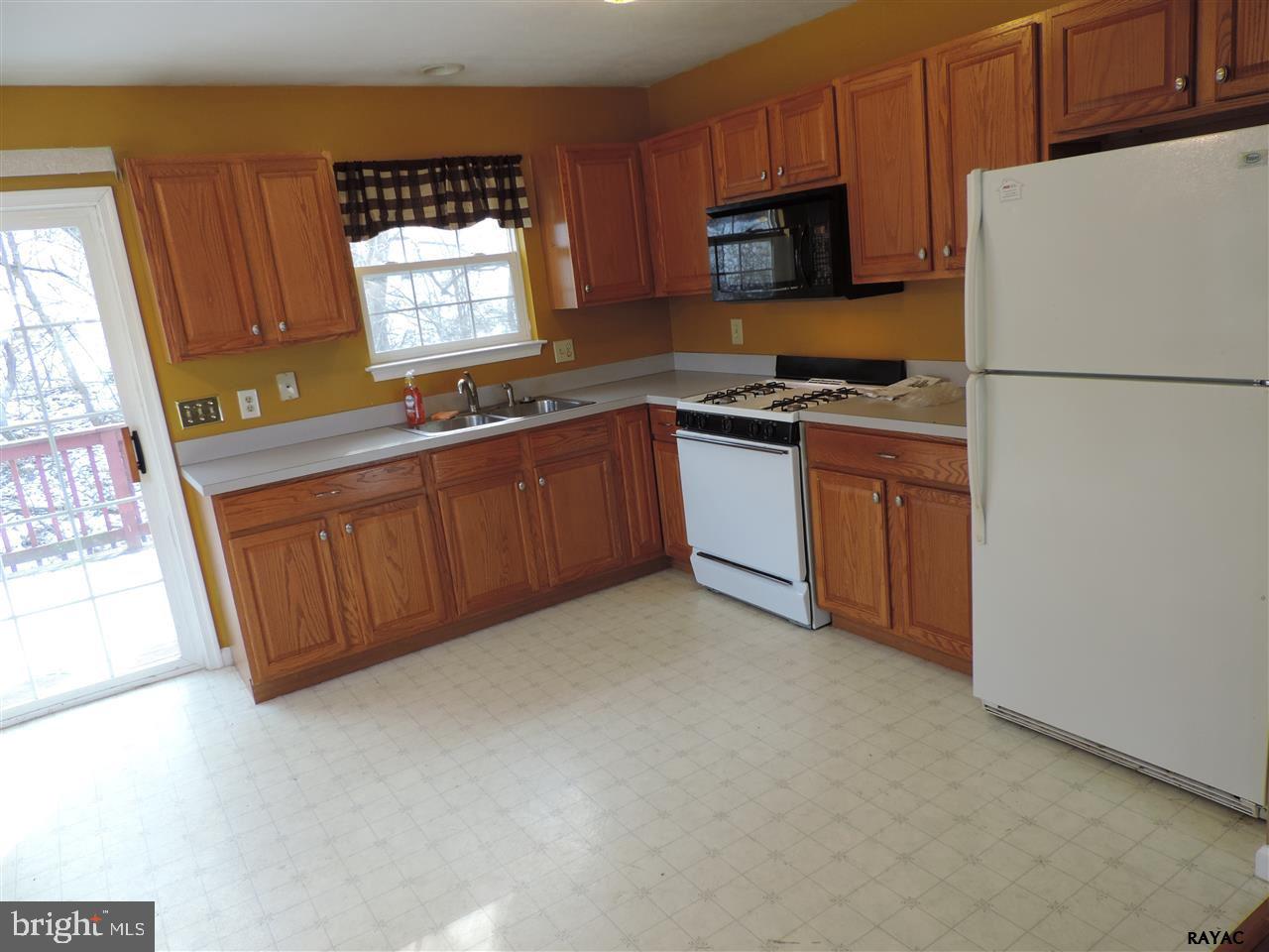 295 Elfner Road Red Lion, PA 17356 - Photo 10 of 27 a kitchen with granite countertop wooden cabinets a refrigerator a stove a sink and a window