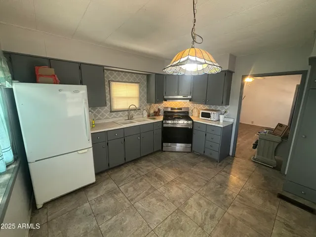 a kitchen with stainless steel appliances granite countertop a refrigerator a sink a stove a washer dryer and a refrigerator