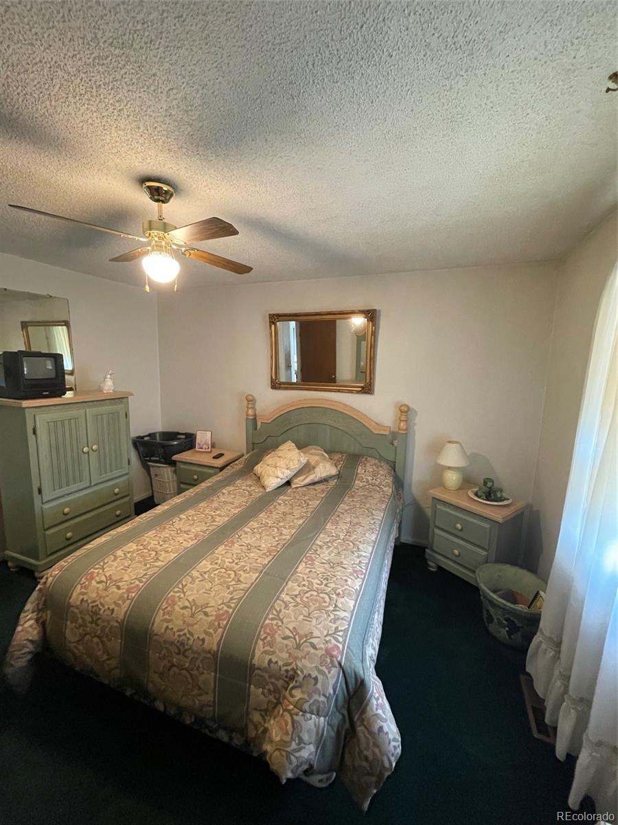 4841 Carson Street Denver, CO 80239 - Photo 8 of 12 a bedroom with a bed and a chandelier