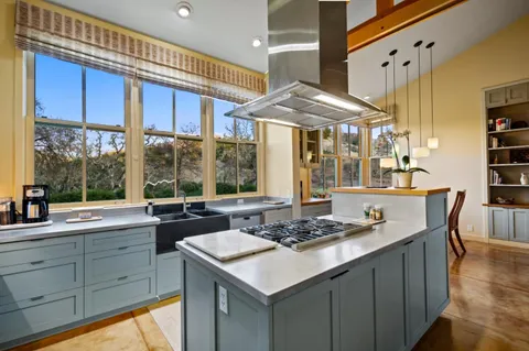 a kitchen with a stove a sink and a dining table with wooden floor