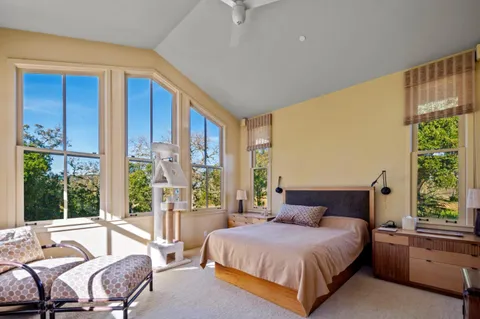 a bedroom with a bed and large windows