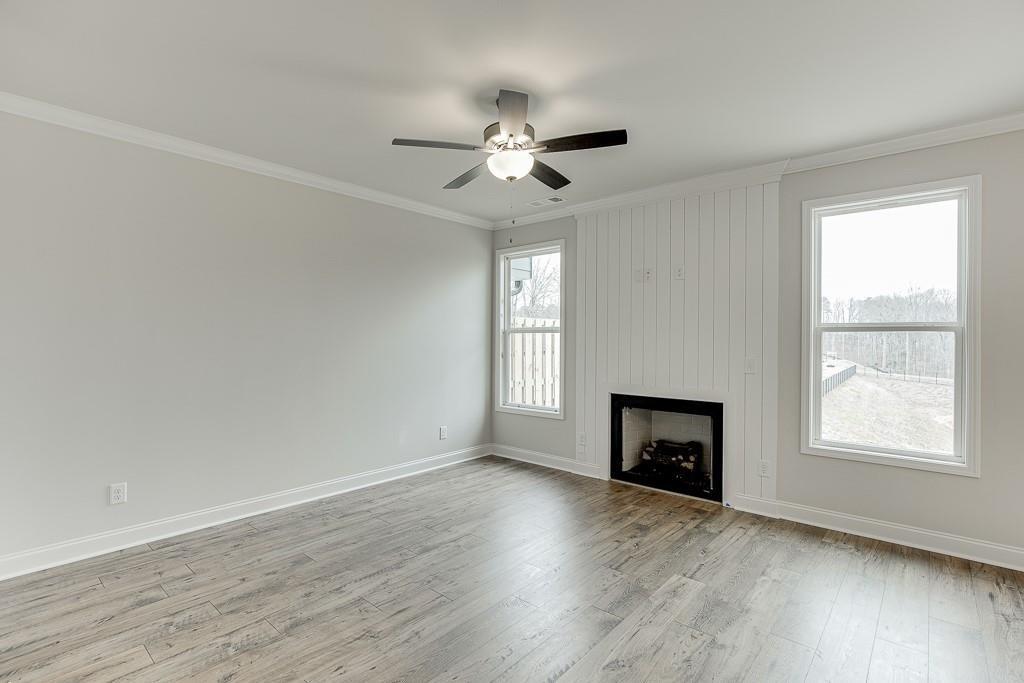 763 Woods Chapel Road Sugar Hill, GA 30518 - Photo 14 of 67 an empty room with wooden floor fireplace and windows