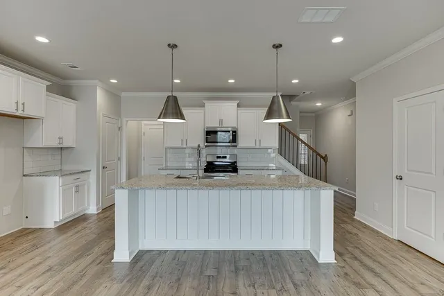 a kitchen with stainless steel appliances granite countertop a sink a microwave a stove and a wooden floors