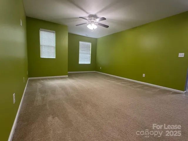 an empty room with windows and chandelier fan