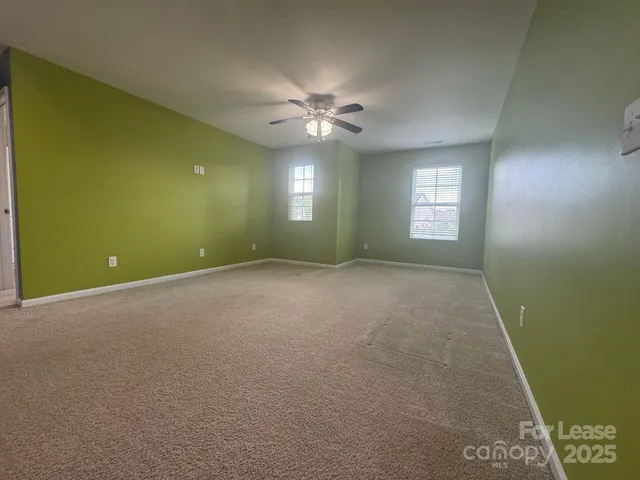a view of an empty room with window and chandelier fan
