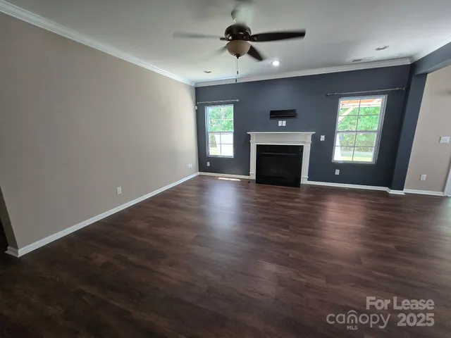 an empty room with wooden floor fireplace and windows