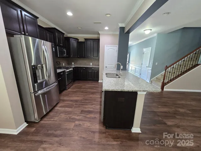 a kitchen with granite countertop a refrigerator and a sink