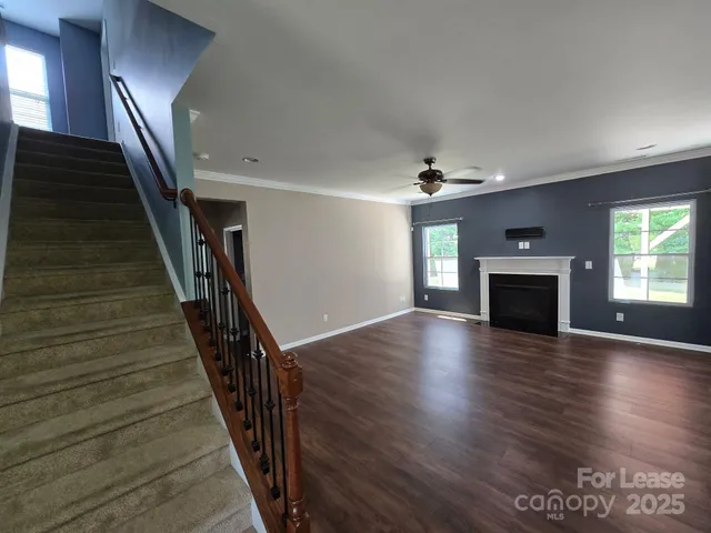an empty room with wooden floor fireplace and windows