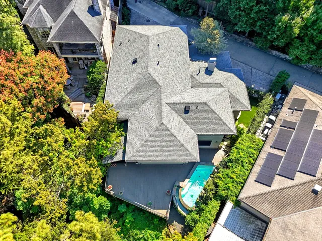 an aerial view of a house with a yard and large trees