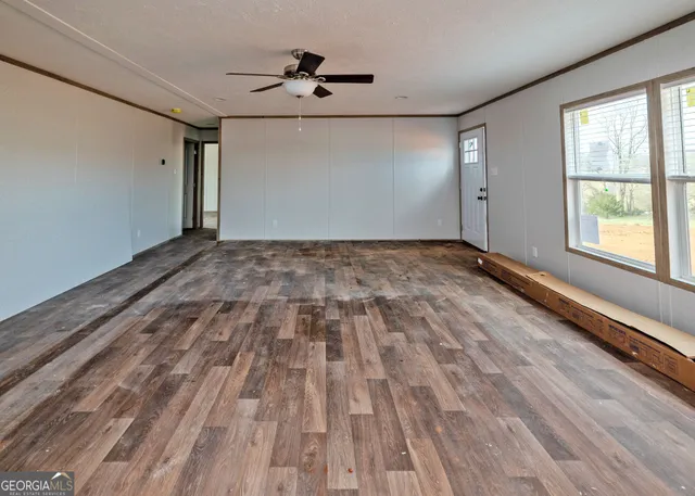 a view of empty room with wooden floor and fan