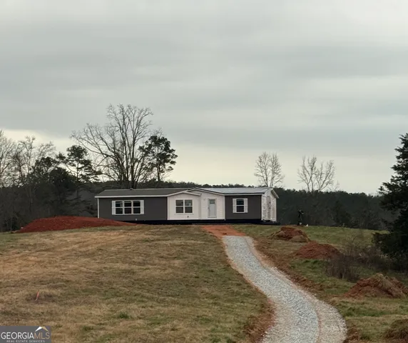 a view of a house with a big yard and large trees