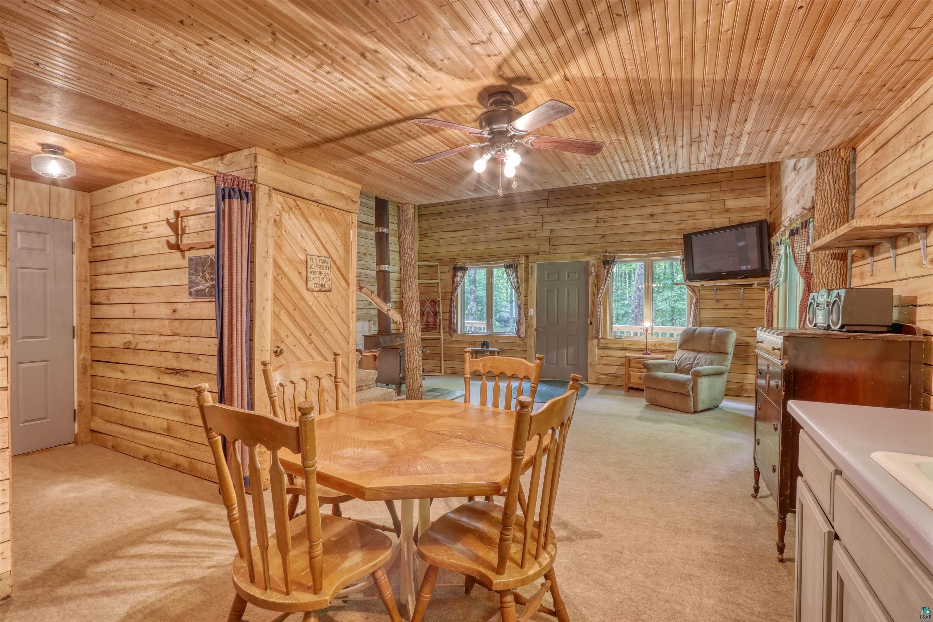 6676 Golf Course Road Winter, WI 54896 - Photo 27 of 51 Dining space featuring wood ceiling, wood walls, light carpet, and ceiling fan