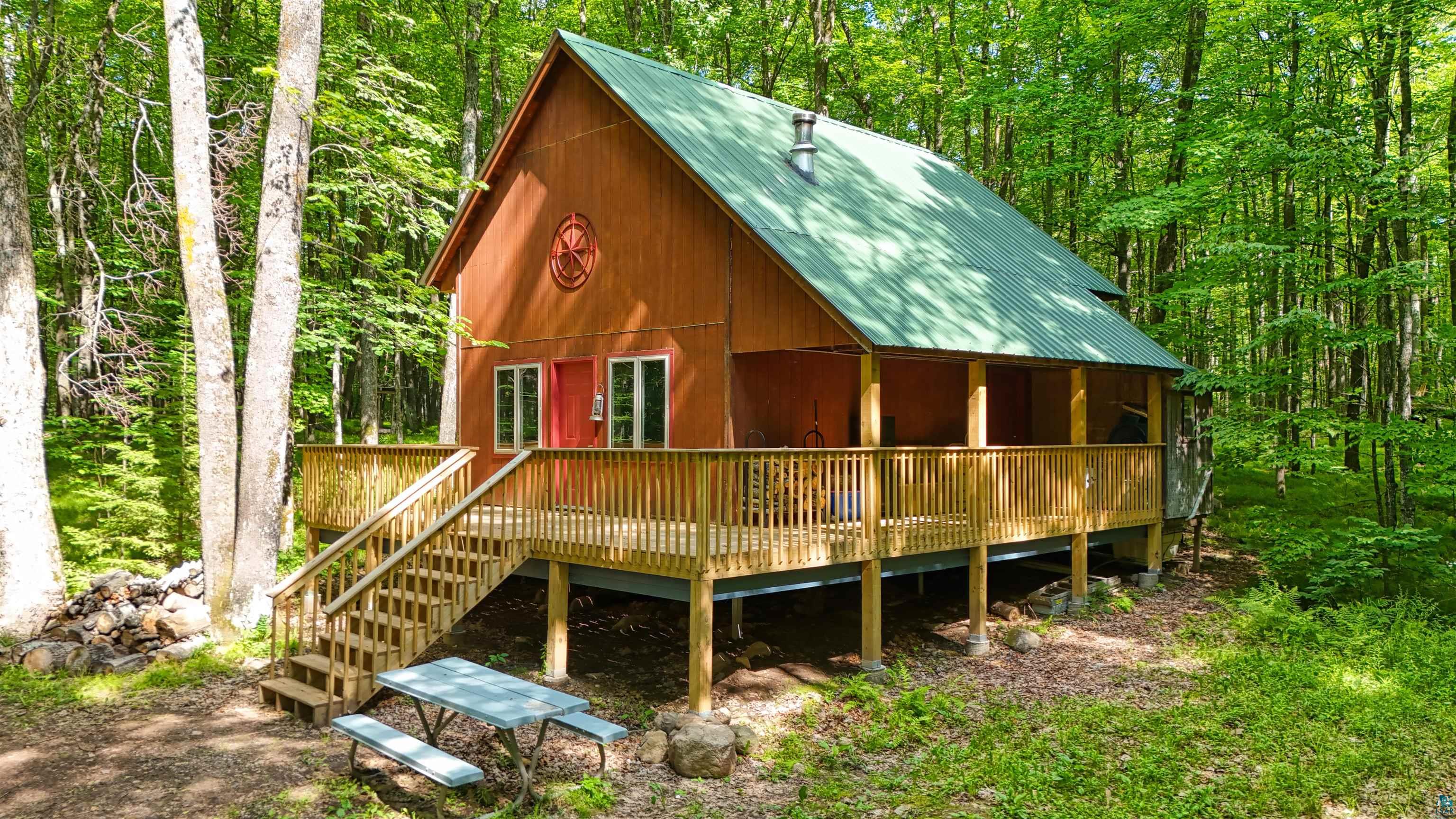6676 Golf Course Road Winter, WI 54896 - Photo 3 of 51 View of front of property featuring a metal roof, a wooden deck, and a forest view
