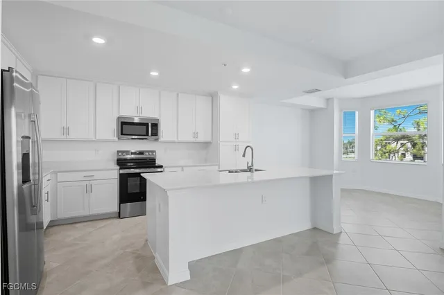 a kitchen with stainless steel appliances a sink a stove a refrigerator with white cabinets