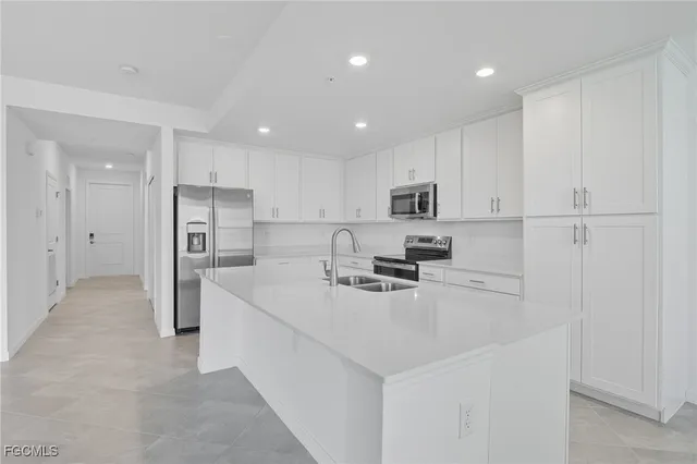 a kitchen with stainless steel appliances a refrigerator sink and white cabinets