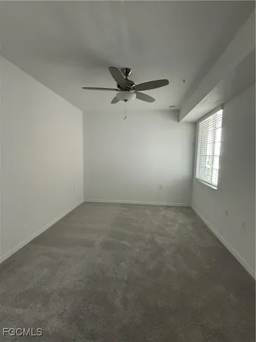 an empty room with a window and a fan