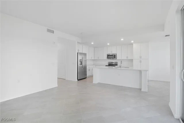 a view of a kitchen with refrigerator and white cabinets