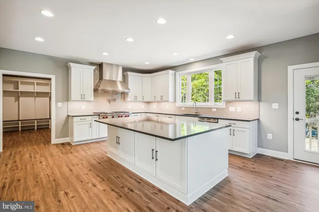 a large kitchen with stainless steel appliances granite countertop a lot of counter space and wooden floors