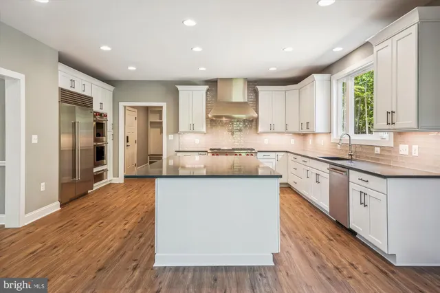 a large kitchen with stainless steel appliances granite countertop a lot of counter space and wooden floors