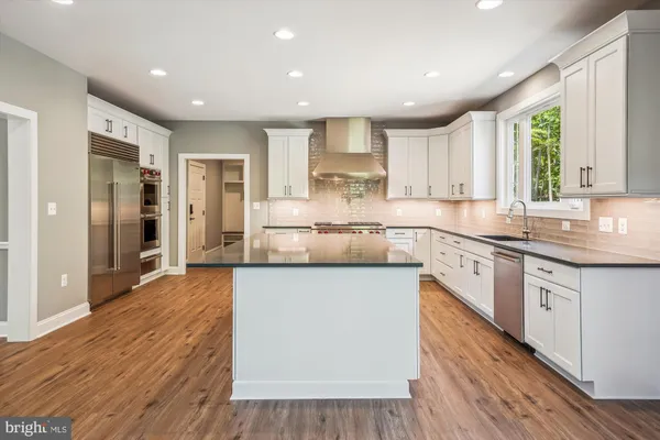 a large kitchen with stainless steel appliances granite countertop a lot of counter space and wooden floors