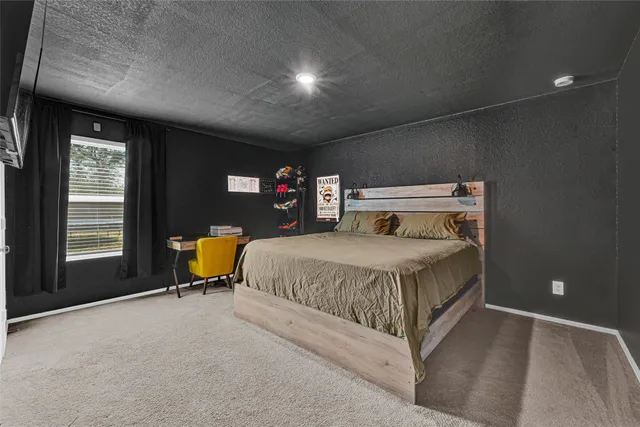 a bedroom with a bed and a flat tv screen on dresser