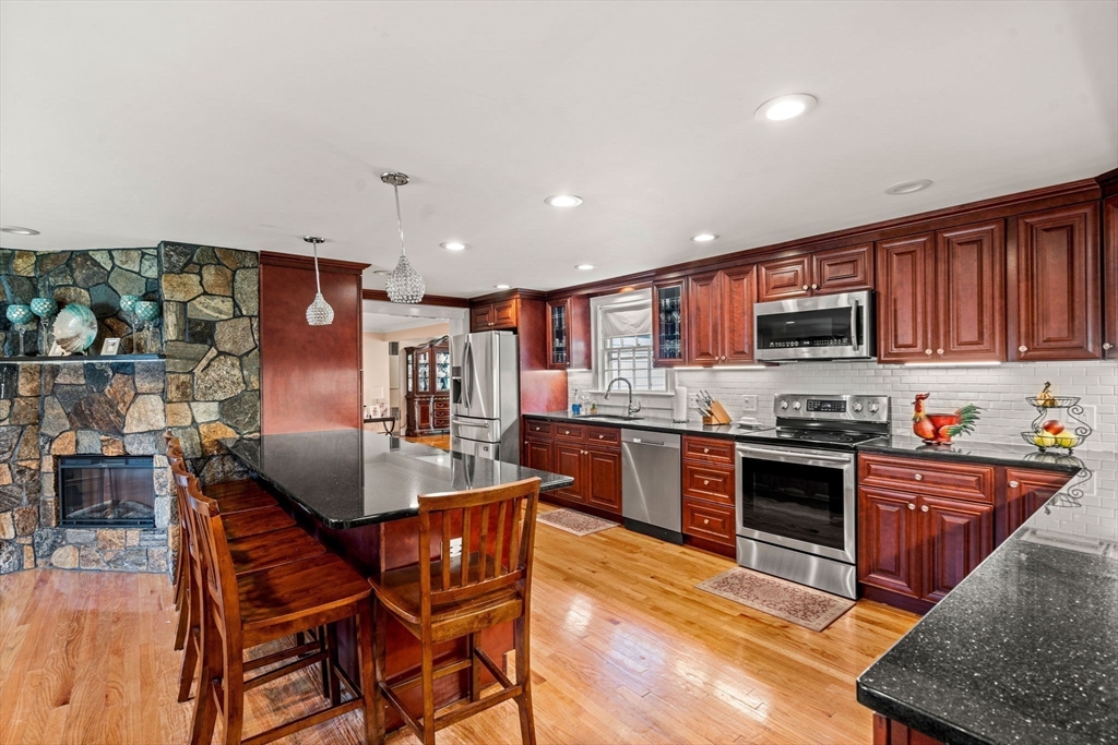 13 Sunnyvale Street Beverly, MA 01915 - Photo 7 of 18 a kitchen with stainless steel appliances granite countertop a stove top oven a sink a dining table and chairs with wooden floor