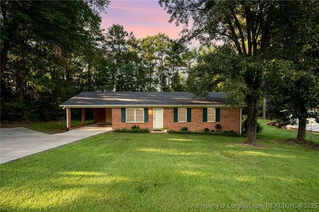 a view of a house with a big yard and large trees