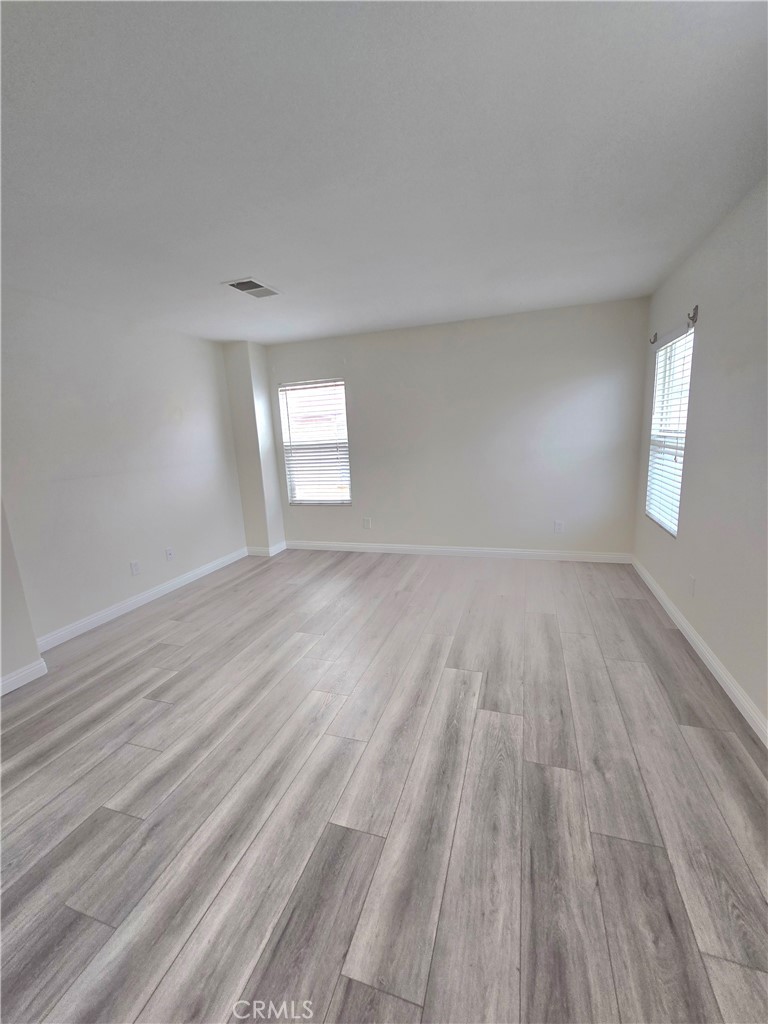 3073 Snowdrop Court Perris, CA 92571 - Photo 19 of 25 an empty room with wooden floor and windows