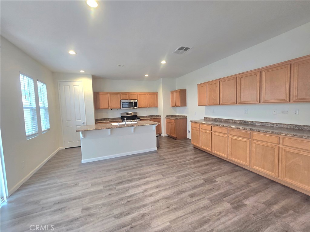 3073 Snowdrop Court Perris, CA 92571 - Photo 4 of 25 a large kitchen with kitchen island a sink wooden floor and stainless steel appliances