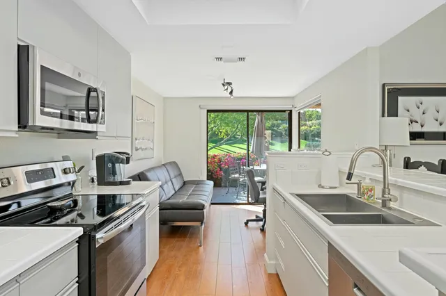 a kitchen with a sink dishwasher a stove and white cabinets with wooden floor
