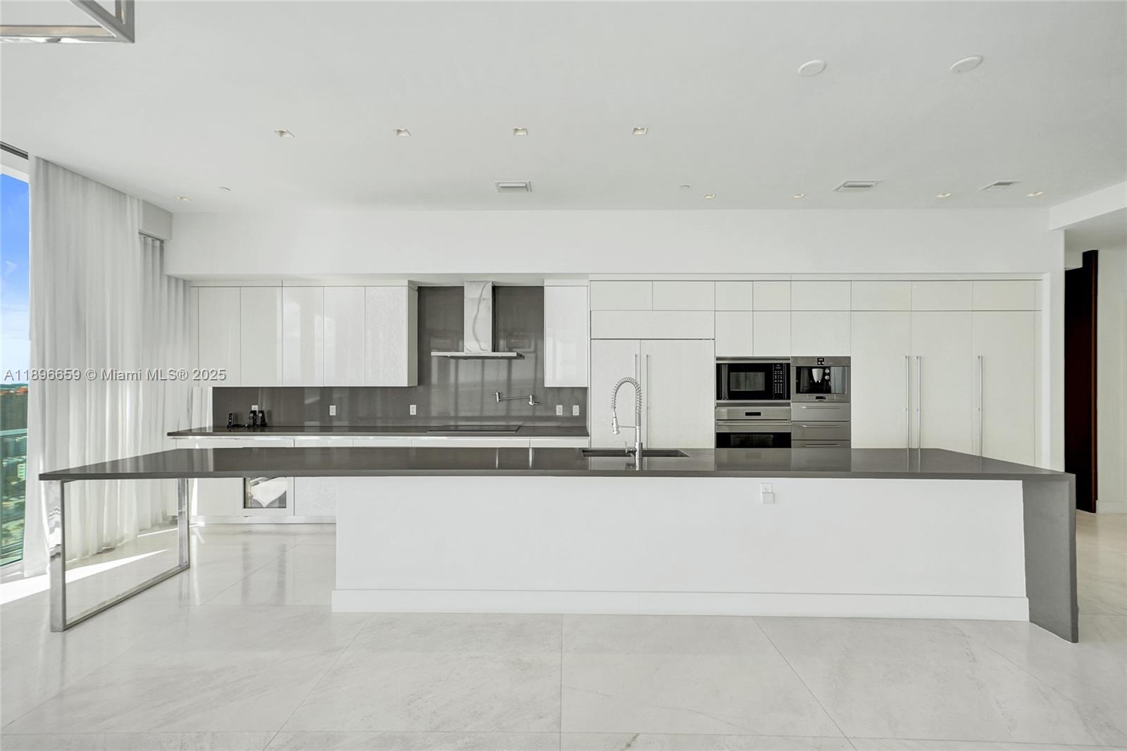 17475 Collins Avenue, Unit 2302 Sunny Isles Beach, FL 33160 - Photo 8 of 42 a large white kitchen with stainless steel appliances