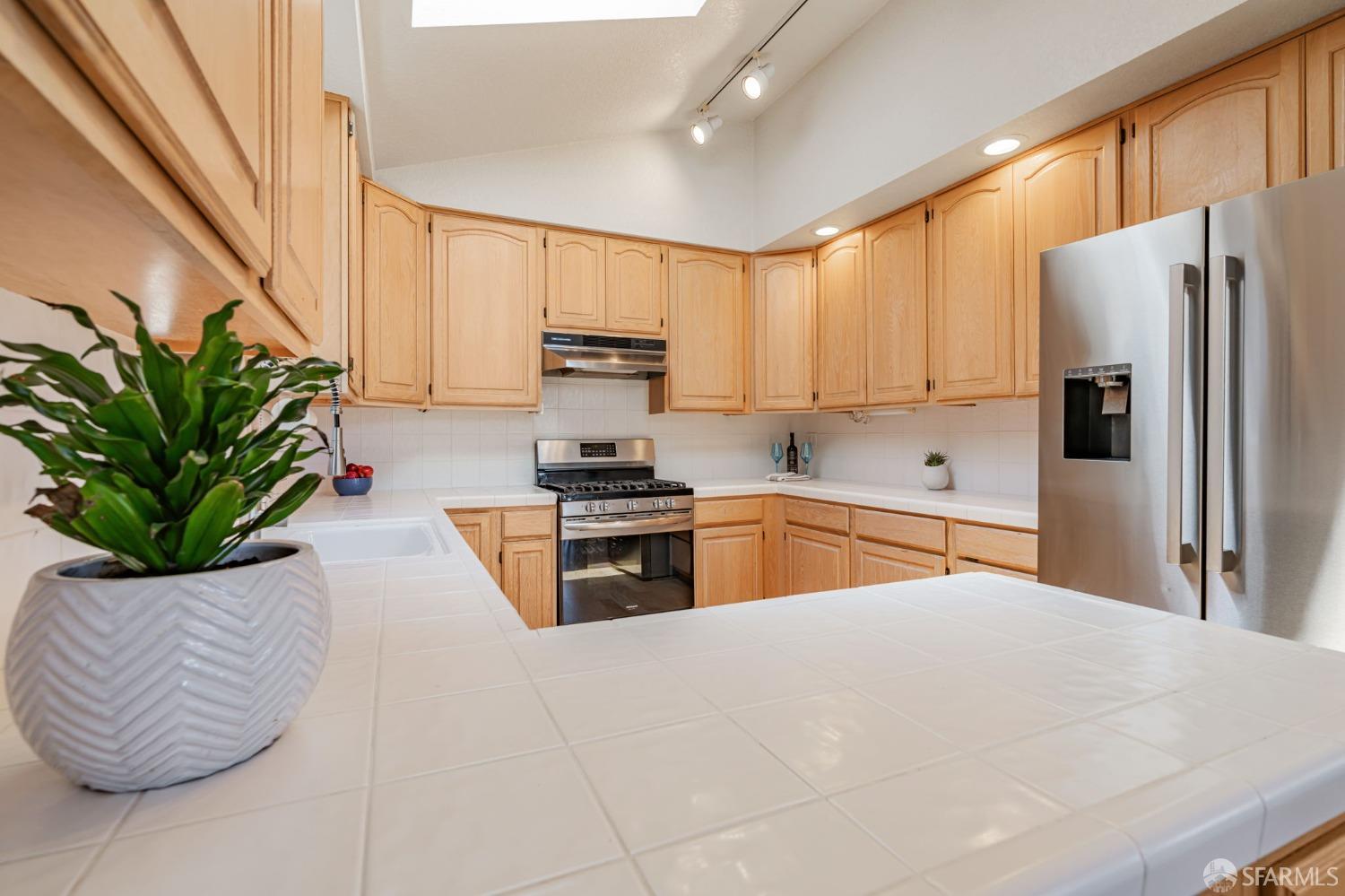 472 Copeland Street Pacifica, CA 94044 - Photo 9 of 31 a kitchen with stainless steel appliances kitchen island granite countertop a refrigerator a sink a stove with wooden cabinets