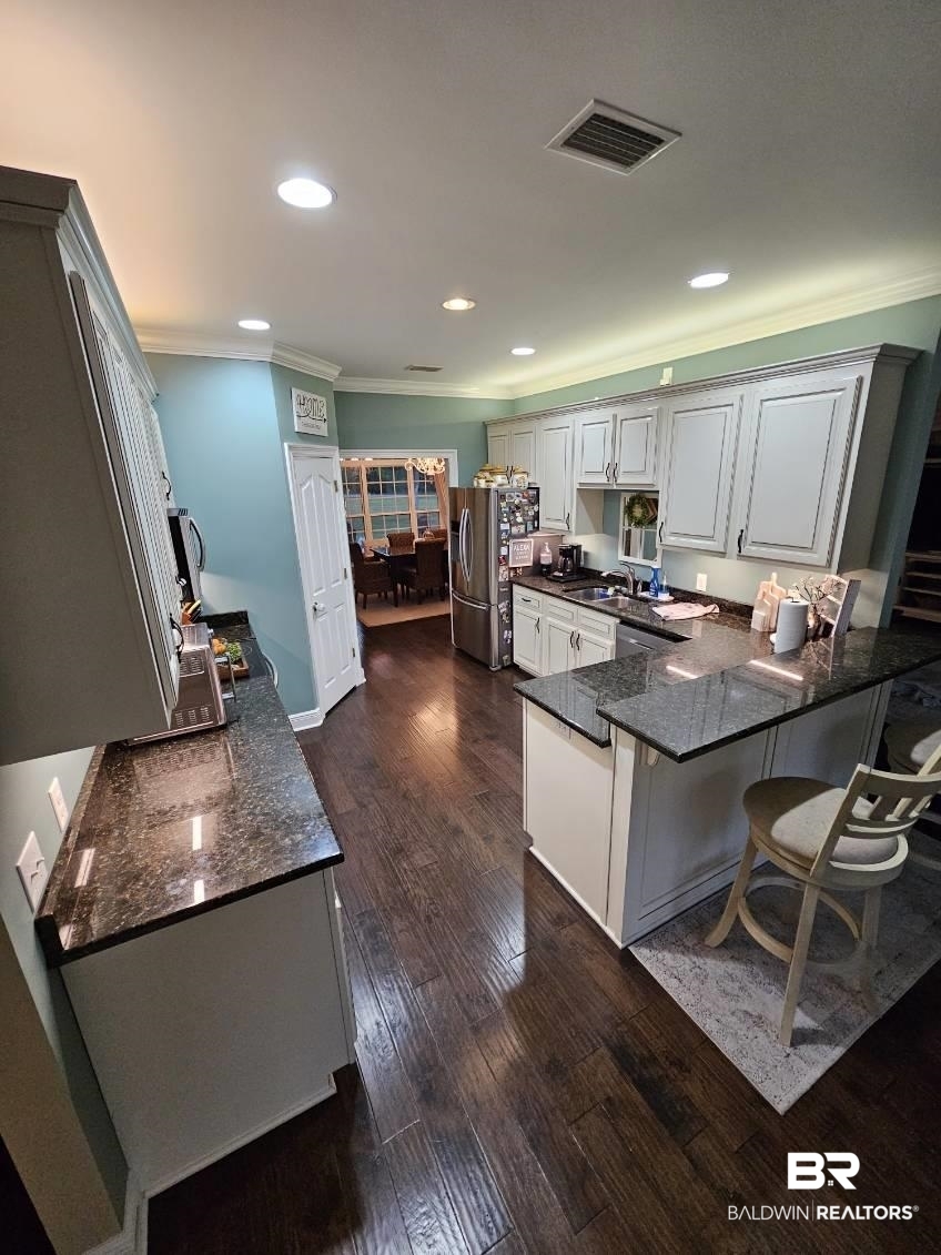 41416 Davis Duck Road Bay Minette, AL 36507 - Photo 24 of 72 Kitchen featuring sink, dark stone countertops, ornamental molding, dark wood-type flooring, and kitchen peninsula