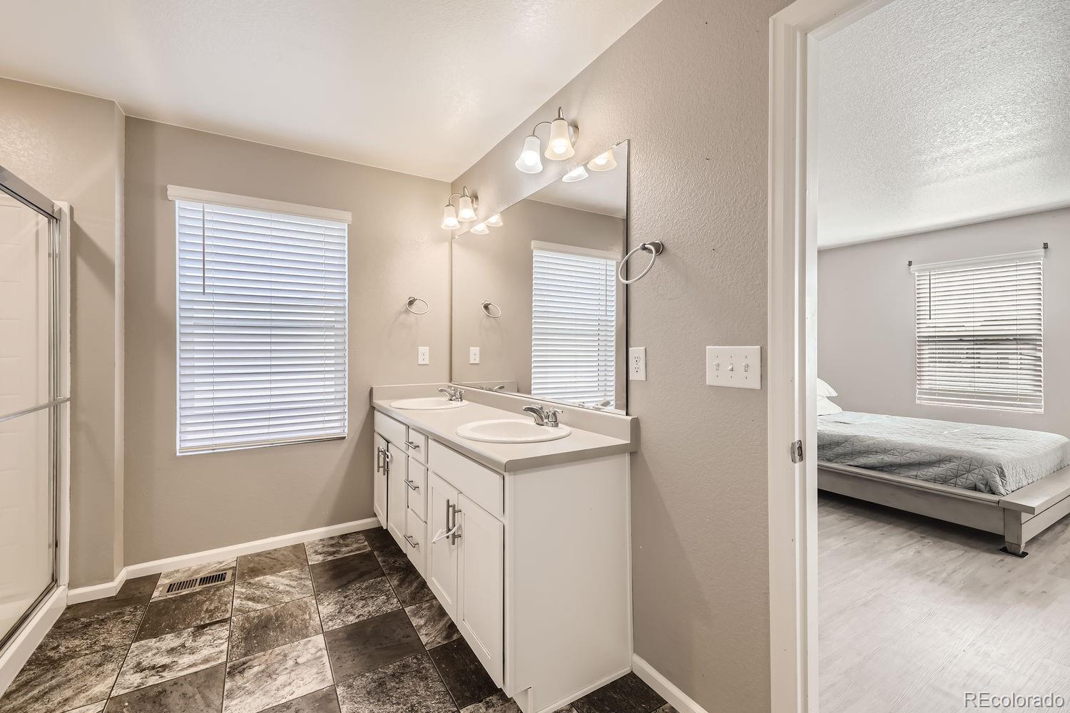 6808 Morrison Drive Frederick, CO 80530 - Photo 21 of 28 a en suite bathroom with a double vanity sink a mirror and a shower