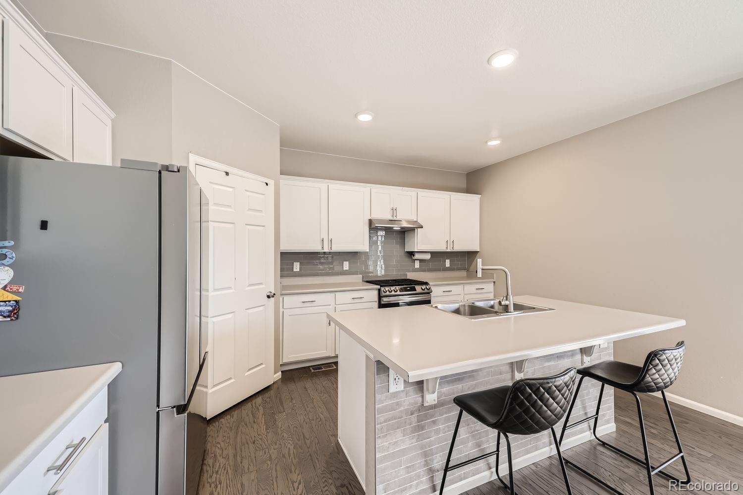 6808 Morrison Drive Frederick, CO 80530 - Photo 5 of 28 a kitchen with a table chairs refrigerator and cabinets
