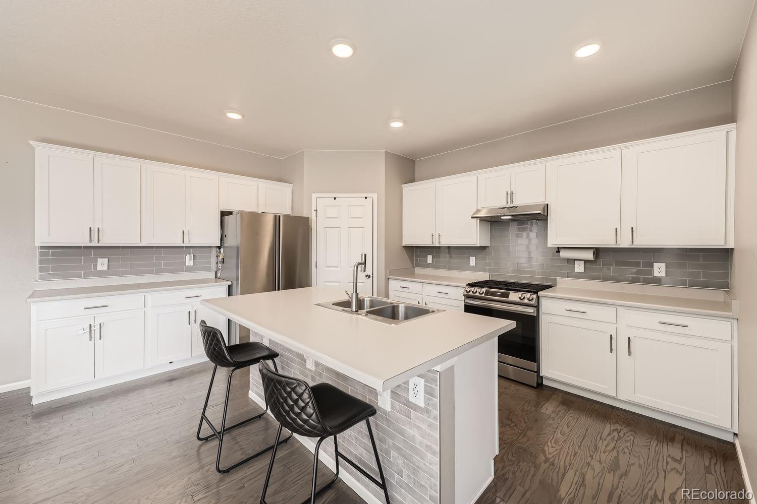 6808 Morrison Drive Frederick, CO 80530 - Photo 6 of 28 a kitchen with a stove a sink a refrigerator and white cabinets