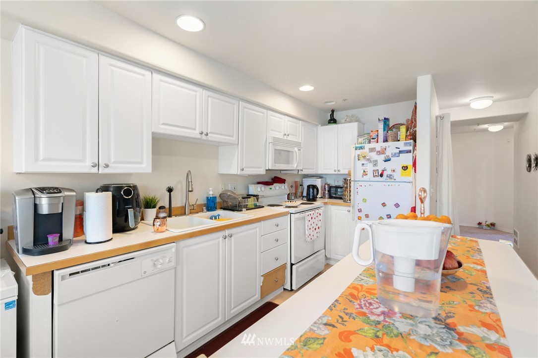 2522 Rucker Avenue, Unit 407 Everett, WA 98201 - Photo 11 of 30 a kitchen with a sink dishwasher and white cabinets with wooden floor