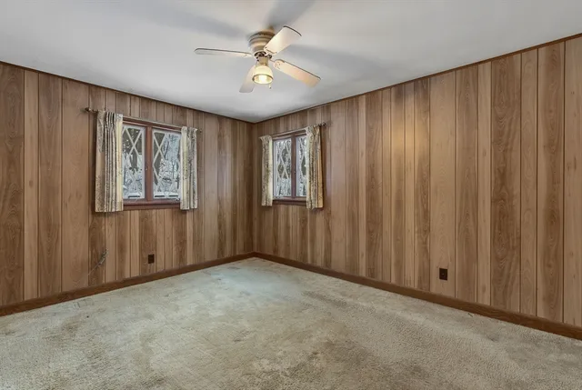an empty room with chandelier fan and windows