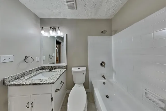 a bathroom with a granite countertop sink a toilet and shower