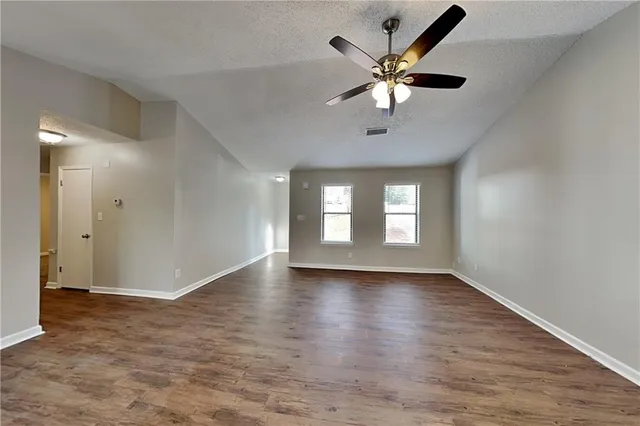 a view of an empty room with window and wooden floor