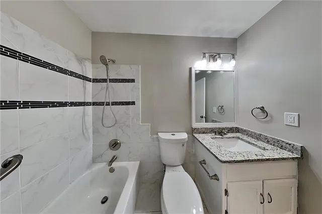 a bathroom with a granite countertop sink a toilet and shower