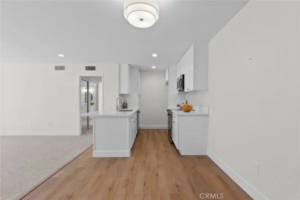 a view of a kitchen with white cabinets and wooden floor