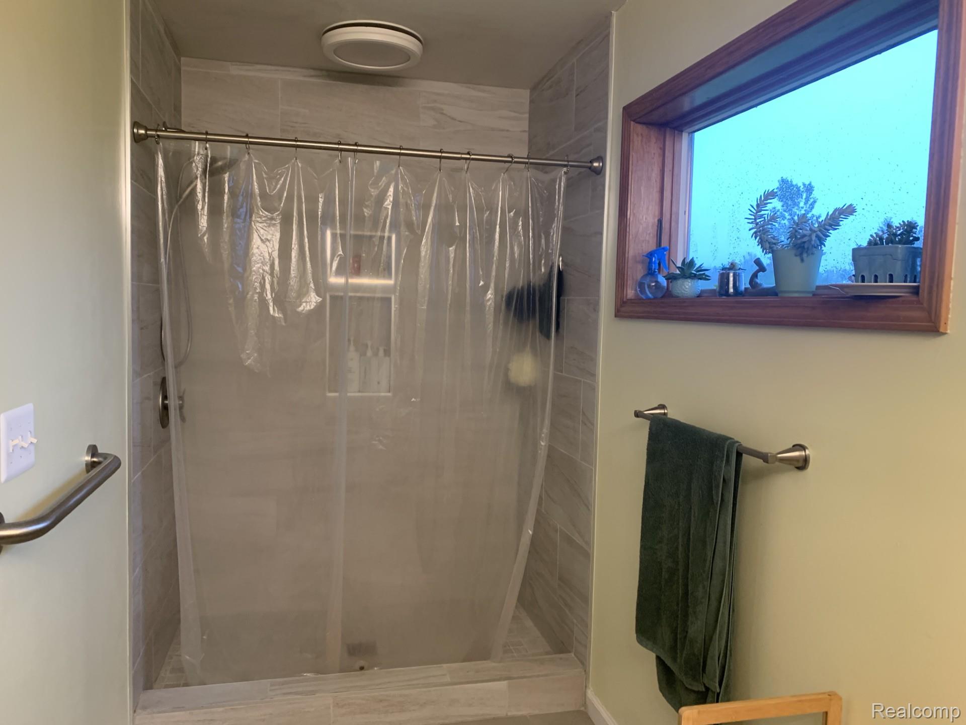 7542 Newberry Road Durand, MI 48429 - Photo 23 of 25 Shower with light-toned tiled walls and flooring, a built-in shower niche, and a window with a wood frame