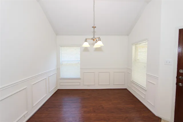 a view of an empty room with wooden floor and windows