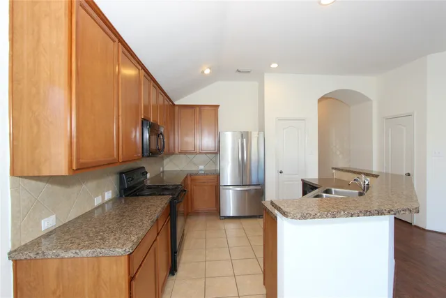 a kitchen with stainless steel appliances granite countertop a sink a stove and a refrigerator