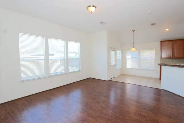 an empty room with wooden floor and windows