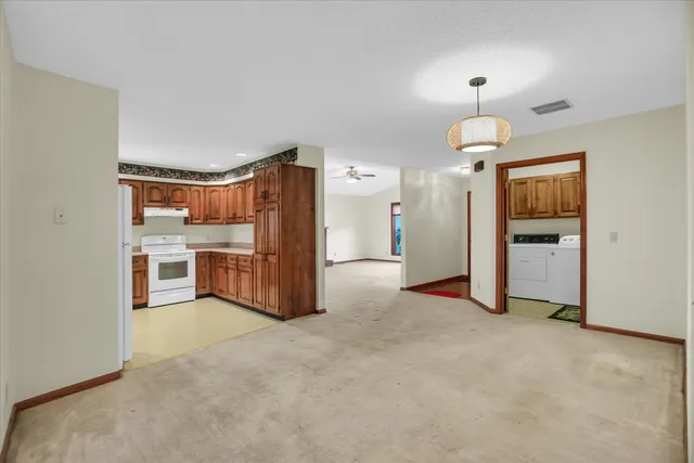 a view of a kitchen with refrigerator and an empty room