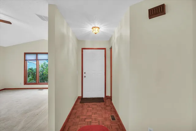 a view of a hallway with wooden floor and a living room